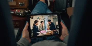 Woman watching KDrama offline on tablet during flight